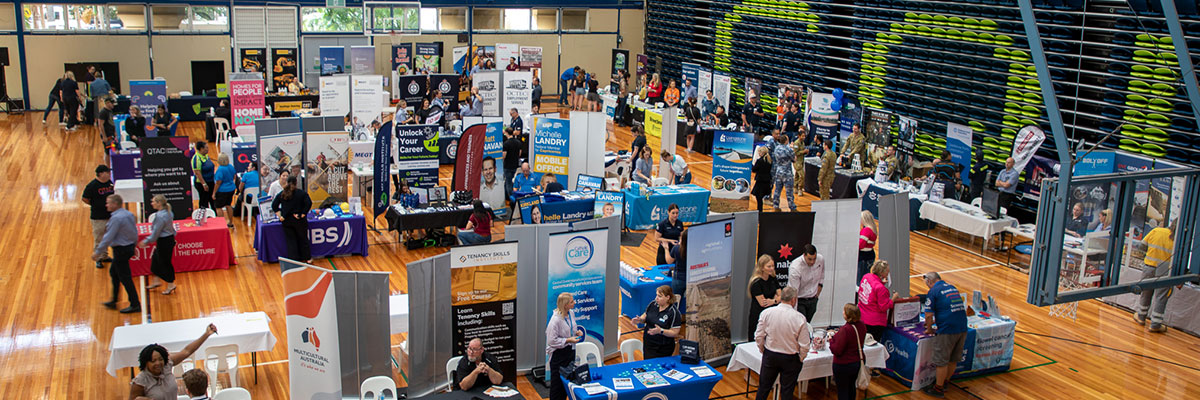 A university hall is filled with exhibitors speaking to students at a careers expo