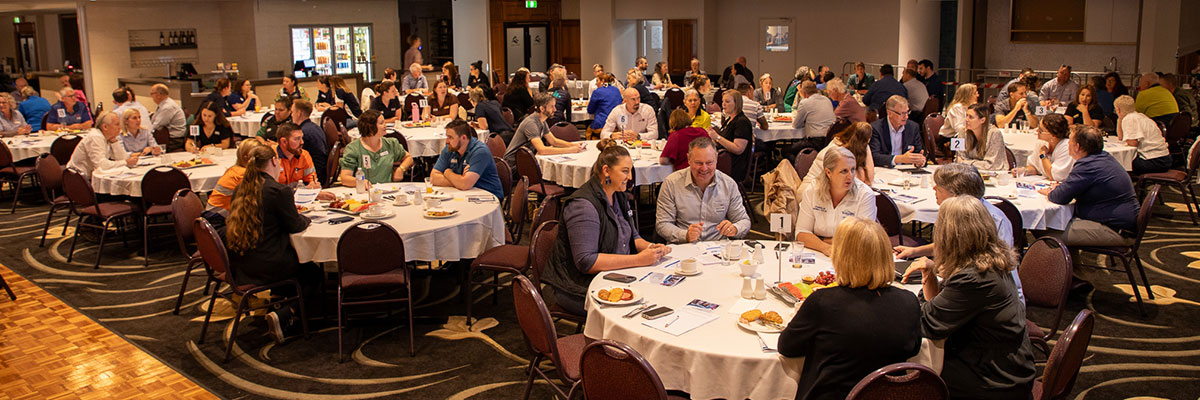 Industry and educational professionals are have discussions at tables spread around a large room