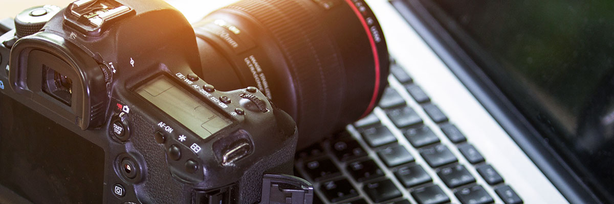 A digital camera is placed on top of a laptop computer