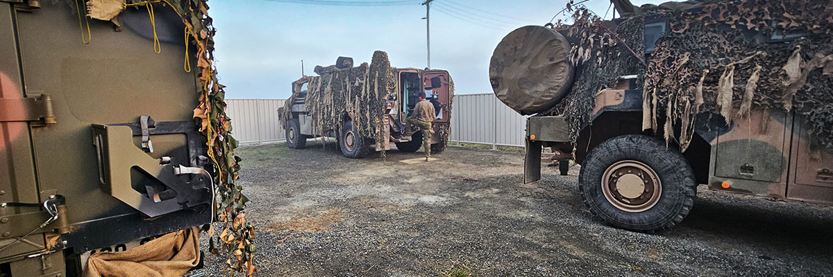 Three military camouflaged four wheel drives parked in a storage facility